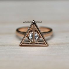 a gold ring with a triangle and a diamond in the middle on a wooden surface