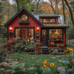 a red house in the woods with lots of flowers