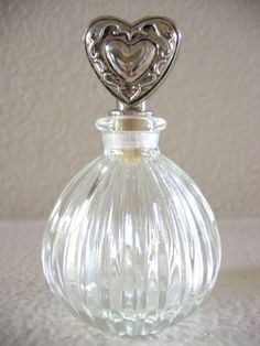 a clear glass bottle with a heart on the top is sitting on a white surface