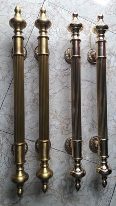 three brass - plated candlesticks are lined up against a marble wall