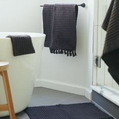 a black towel hanging on the wall next to a bathtub