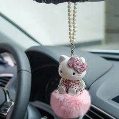 a hello kitty keychain hanging from the dashboard of a car with pearls on it