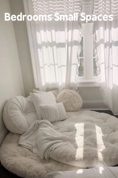 a large round bed in front of a window with white curtains and pillows on it