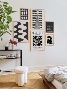 a bedroom with posters on the wall and a bed in the foreground, next to a potted plant