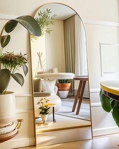 a mirror sitting on top of a table next to a potted plant in a vase