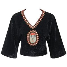 Extremely rare vintage Gucci c.1970's black crushed velvet cropped blouse. Bohemian beaded and embroidered detail at neckline and center front made up of blue and red rounded glass beads, faceted tear drop crystals with red and gold surrounding embroidery, and embroidered face detail. Short dolman sleeves. V-neckline. Banded waist. Crop style. Center back zipper with two hook and eye closures at hem. Fully lined in black signature "Gucci" lining. Please note sleeves have been altered to a shorte Clothing Blouses, Beaded Crop Top, Vintage Blouses, Fashion 70s, Boho Crop Tops, Embroidered Crop Tops, Embroidered Face, Crop Style, Bohemian Blouses