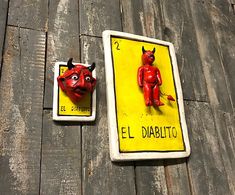 two red devil magnets sitting on top of a wooden table next to each other