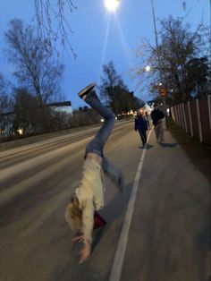 a person doing a handstand on the side of a road with their feet in the air