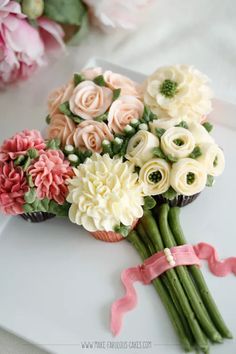 a bouquet of flowers sitting on top of a white table next to a cupcake