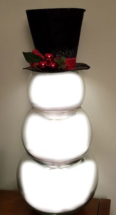 a stack of white balls with a top hat on it's head and some red berries in the middle