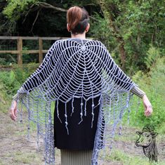 a woman is walking in the grass with her back to the camera, covered by chains