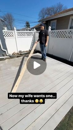 a man standing on top of a wooden deck next to a white fence and house