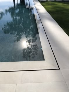 an empty swimming pool in the middle of a grass covered yard with palm trees on either side