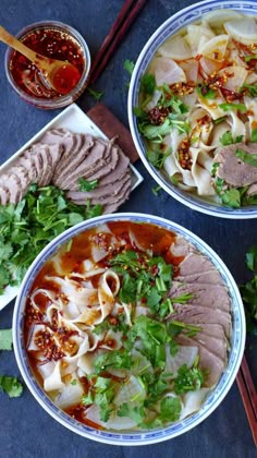 two bowls filled with noodles, meat and veggies next to chopsticks