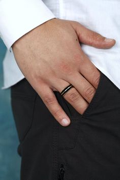 a man wearing a wedding ring on his left hand, with the other hand in his pocket