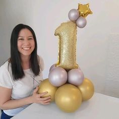 a woman is holding a balloon in front of a cake with the number one on it