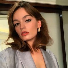 a woman with brown hair and earrings posing for a photo in front of a mirror