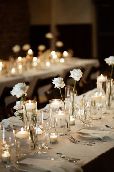 a long table is set with candles and flowers in glass vases on the tables