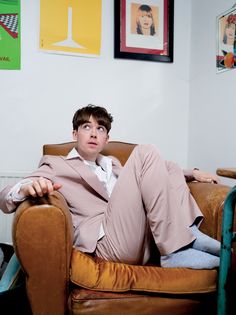 a young man sitting on top of a brown chair