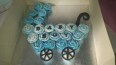 a cake in the shape of a baby carriage with blue roses on it's wheels