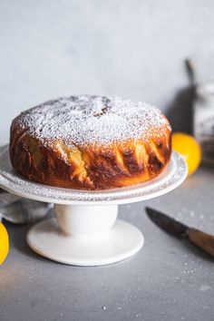 a cake sitting on top of a white plate next to some lemons and knife