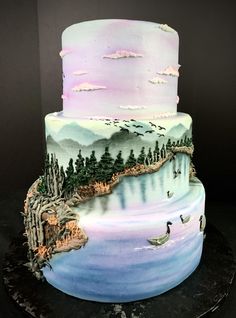 a three tiered cake decorated with water and trees