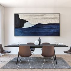 a dining room table with four chairs and a large painting on the wall above it