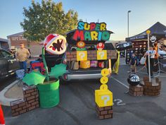 a group of people standing in front of a car with mario decorations on the back