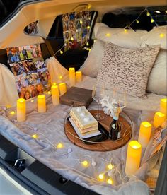 a table with candles and cake on it in the trunk of a car that is parked