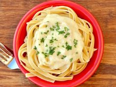 a red plate topped with pasta covered in sauce and garnished with parsley