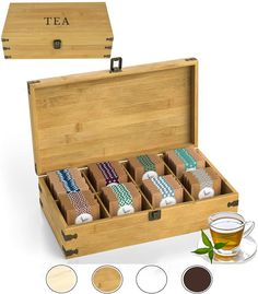 a wooden box filled with teas next to a cup and saucer on top of a table