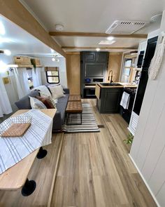 a living room and kitchen area in an rv with wood flooring on the walls