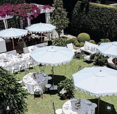 an aerial view of tables and umbrellas on the lawn in front of some bushes