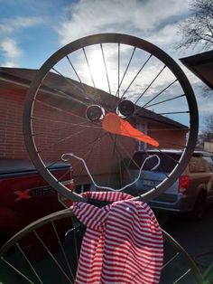 an old bicycle wheel has been decorated with red and white checkered fabric as it stands in front of a house