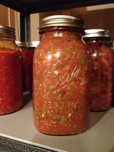 jars filled with different kinds of food on top of a shelf next to a stove