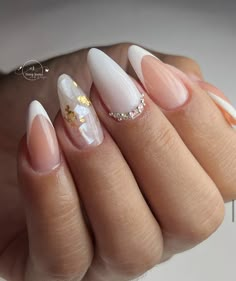 a woman's hand with some white and gold nails