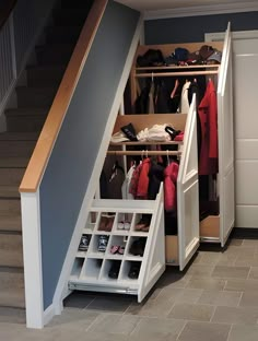 a closet under stairs with clothes and shoes