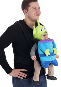 a man is holding a baby in a toy alien costume while smiling at the camera