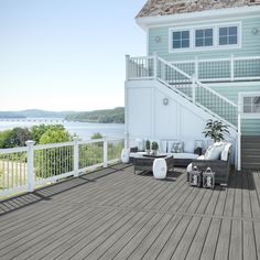 a deck with furniture and stairs leading up to a house on the water's edge