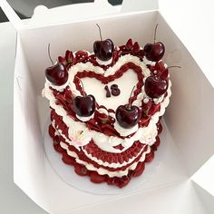 a heart shaped cake with cherries on top in a box