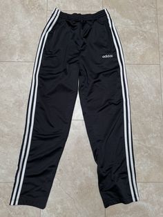 These pants are super hip, and ready for balling out. They are old school Adidas. The buttons have the three stripes logo on them, classic. They must be bought to be worn.  Brand: Adidas Size: Small Material: Polyester Measurements in inches Waist 26-30 Inseam 29 1/1.2 #43 I do accept returns within 30 days of purchase of all vintage items. The item must be in the same condition in which it shipped and preferably with the tags still on. The customer is responsible for all shipping costs and there is a 20% restocking fee for all returns. Y2k Adidas Pants, 2000 Track Pants, Track Pants Adidas, Vintage Adidas Track Pants, Adidas Logo Black Jogging Pants, Adidas Hose, Adidas Vintage, Black Tears, Adidas Pants