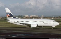 a large passenger jet sitting on top of an airport tarmac with buildings in the background