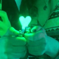 two people are holding up their cell phones with the light shining on them in the shape of a heart