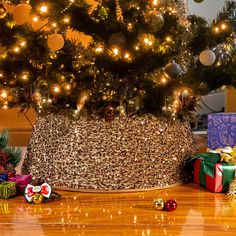 a small christmas tree in a basket with presents underneath it and lights on the trees