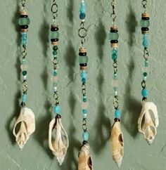 several seashells are hanging on a wall with beads and chains attached to them