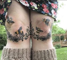 two women with tattoos on their legs standing in the grass