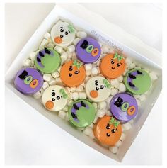 a box filled with lots of decorated cookies in different shapes and colors on top of marshmallows