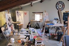 an artist's studio with easels and paintings