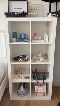 a white book shelf filled with purses and other items on top of a hard wood floor