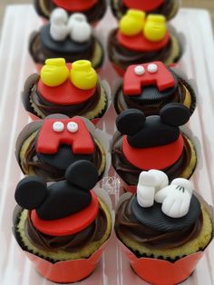 mickey mouse cupcakes with chocolate frosting and fondant decorations on top are displayed